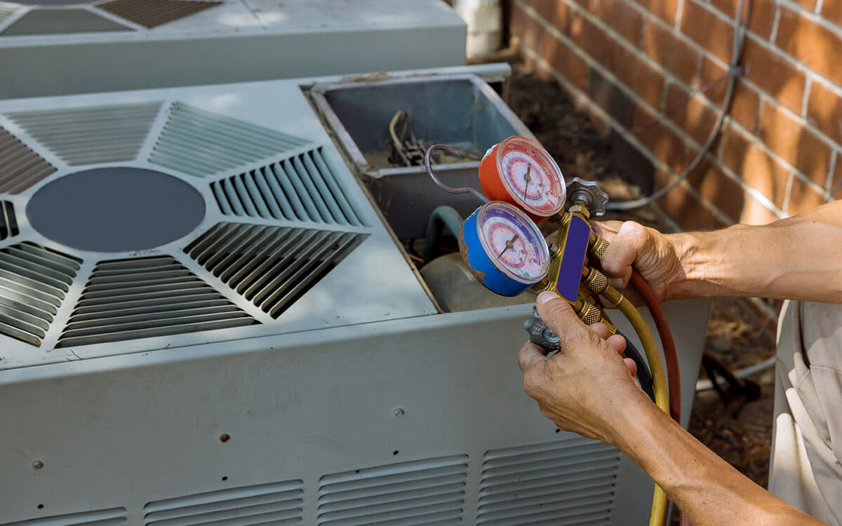 A technician checking refrigerant pressure on an AC unit